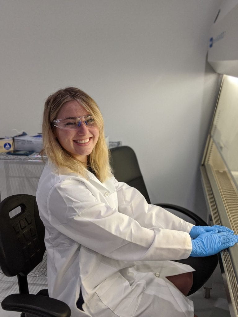 Student smiling at research bench 