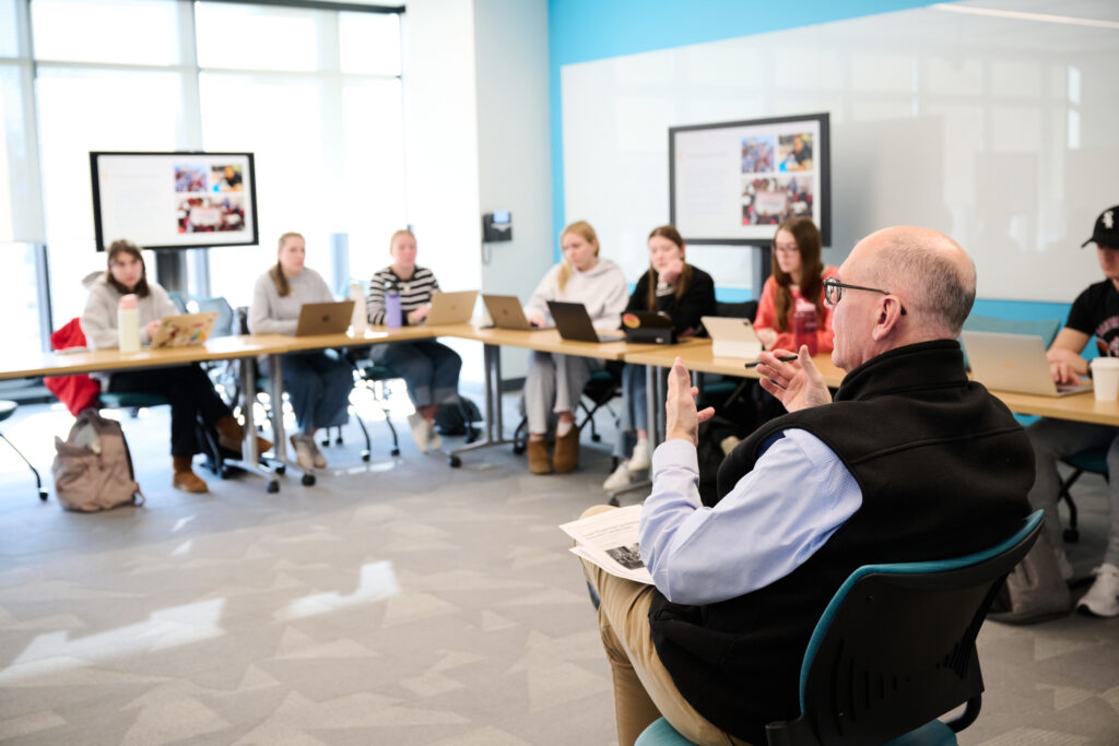 Faculty member speaks to group of students in Mondor Center classroom.